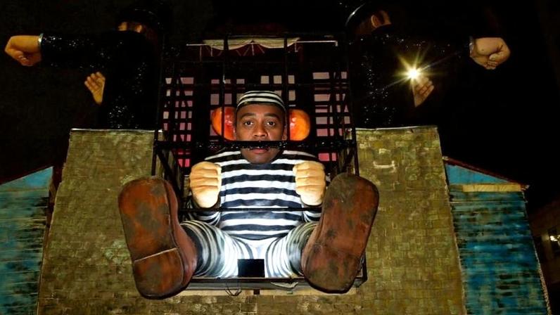 Carro alegórico do desfile da Acadêmicos de Niterói, em homenagem a Lula, mostra palhaço preso com tornozeleira eletrônica danificada.