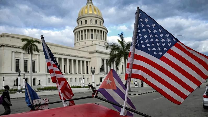 Two U.S. flags and a Cuban flag flutter on the roof of a vehicle in Havana on Feb. 3.