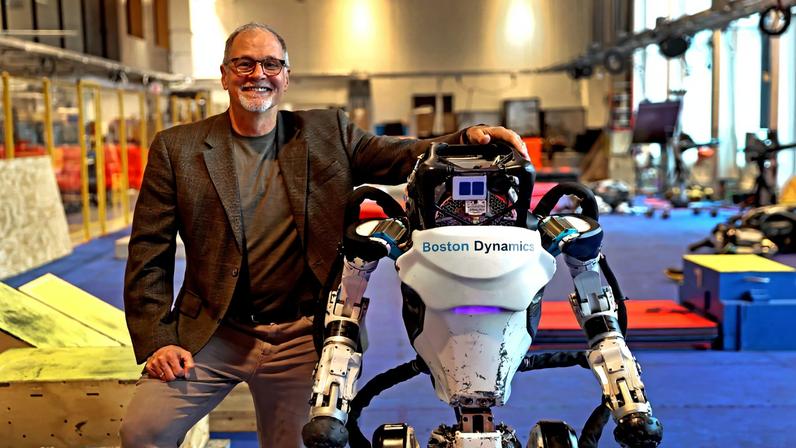 Former Boston Dynamics CEO Robert Playter sitting with a prototype of the company’s Atlas robots
