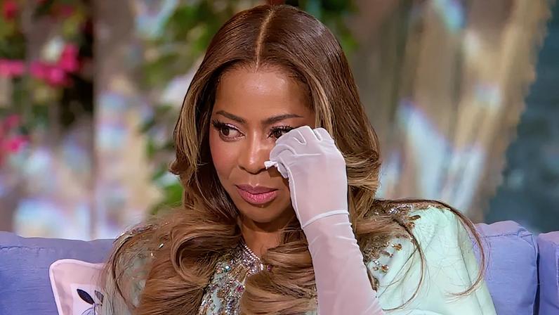 Mary Cosby wiping her eye with a white-gloved hand while looking distressed.