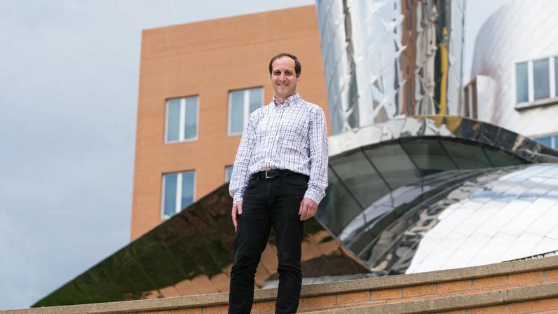 Antonio Torralba stands on the top rung of the Stata Amphitheatre on MIT's campus. The Stata Center is behind him.