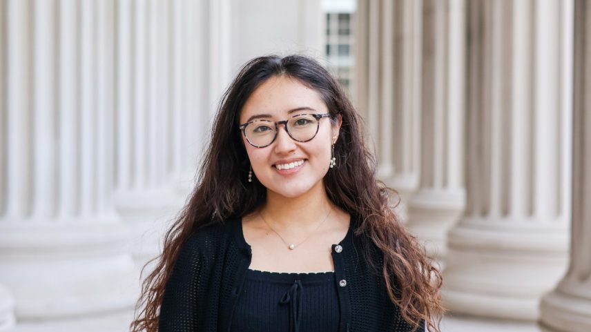 Katie Spivakovsky stands before outdoor columns at MIT