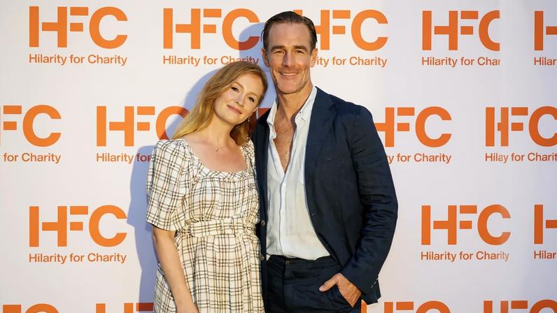 James Van Der Beek and Kimberly Van Der Beek pose in front of a white Hilarity for Charity backdrop.