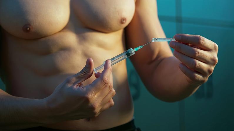 Close de um atleta musculoso segurando uma injeção de substâncias para melhorar o desempenho.