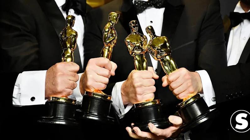 Fotografia de quatro homens segurando estatuetas do Oscar.