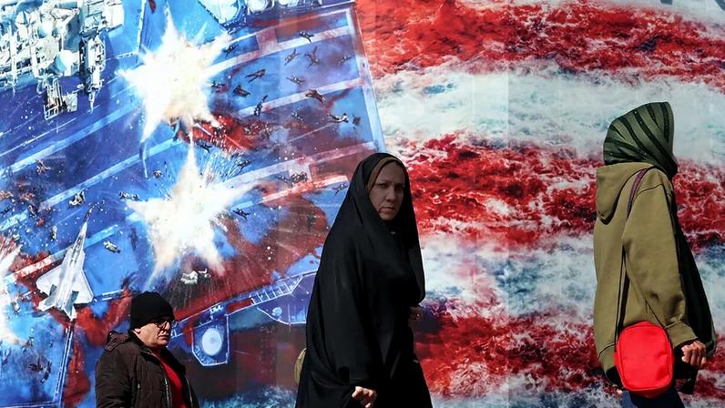 Iranians walk past an anti-US billboard at Enqelab Square in Tehran, Iran, 16 February 2026