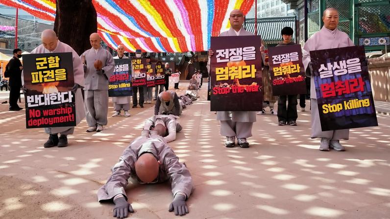 South Korean Buddhist monks and members of civic groups bow and prostrate themselves as they march towards the U.S. Embassy in Seoul, South Korea, to protest against President Donald Trump, March 17, 2026.