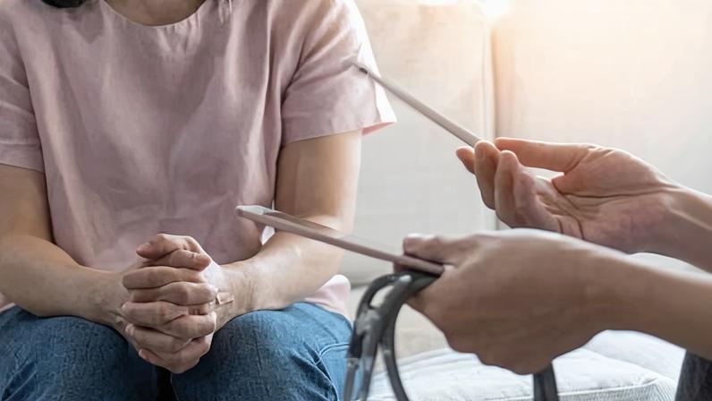 Women sitting with hands clasped talking to doctor