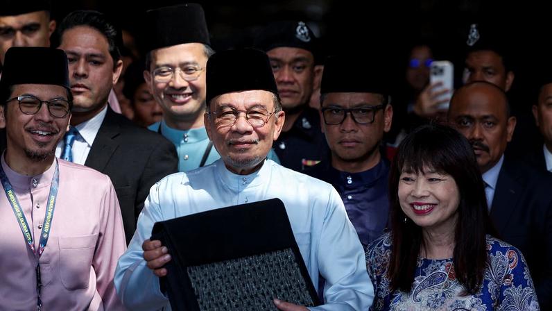 Malaysia's Prime Minister and Finance Minister, Anwar Ibrahim, holds the 2026 national budget document at the Finance Ministry building as he departs for Parliament to table the budget, in Putrajaya, Malaysia, October 10, 2025. REUTERS/Hasnoor Hussain/File Photo