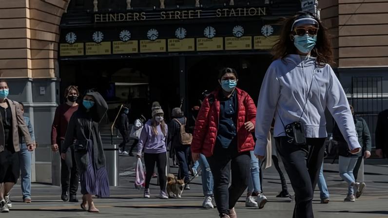 Pedestrians cross a street outside Flinders Street Station on October 24, 2021 in Melbourne, Australia.