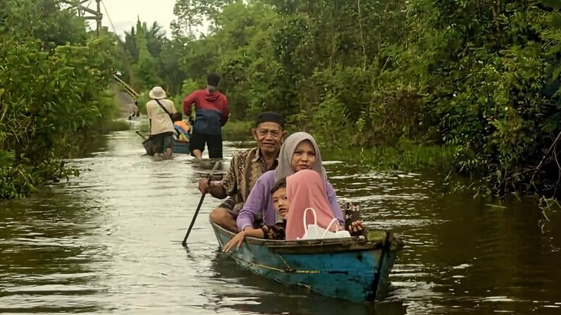 Residents use canoes to navigate the floodwaters in Banjar Regency.