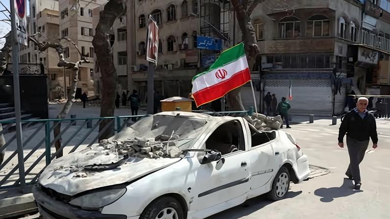 A man walks past an Iranian flag fluttering above the wreckage of a car in Tehran, on 4 March 2026.