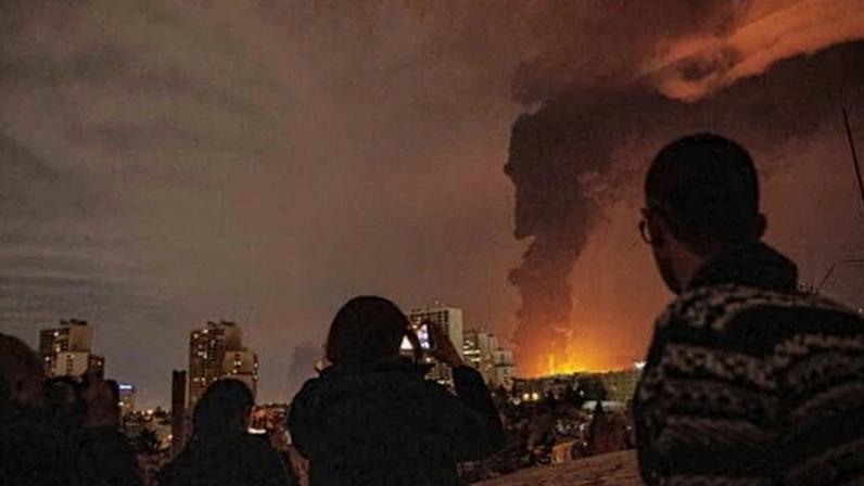 Residents watch as flames and smoke rise from an oil storage facility struck during the US–Israeli military campaign in Tehran on Saturday.