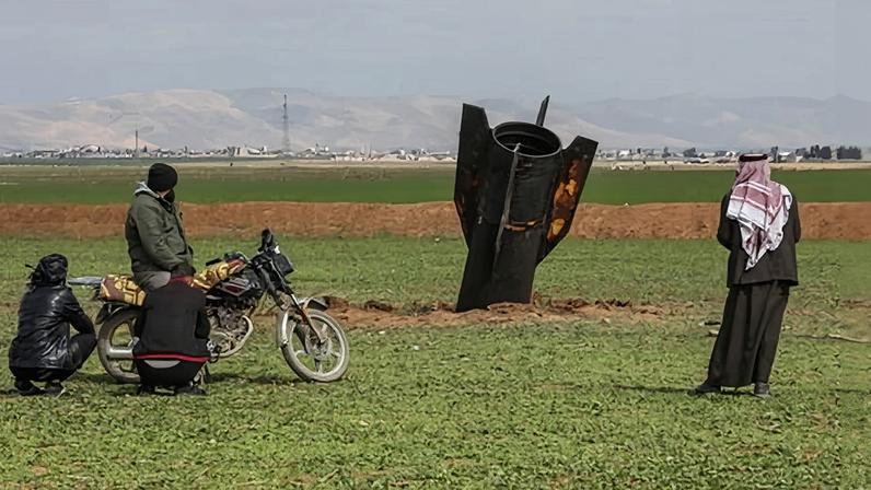 People stand next to an Iranian missile after it fell near Qamishli international airport, Syria, amid the US-Israel war with Iran.