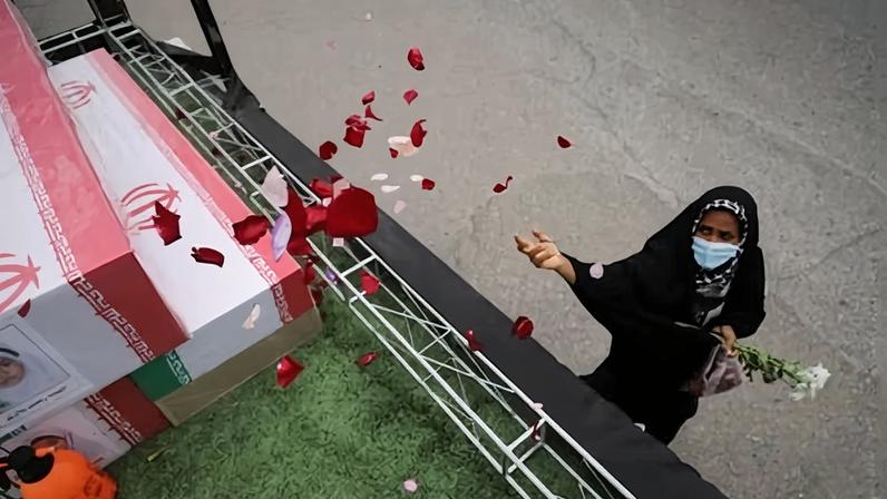 A woman throws rose petals on the coffins during funeral of children killed in a strike on 28 February on a girls' elementary school in Minab, Iran.