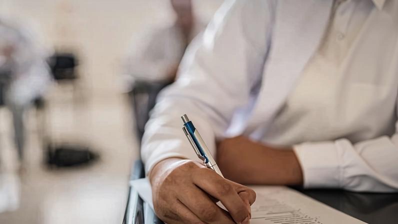Close-up of student woman writing on educational exam on classroom at university