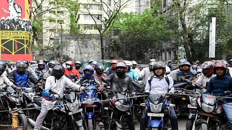 Motorcyclists wait behind a rope for their turn to get fuel at a pump in Dhaka, Bangladesh, on Sunday. The South Asian country has deployed the military to major oil depots and police around fuel stations.