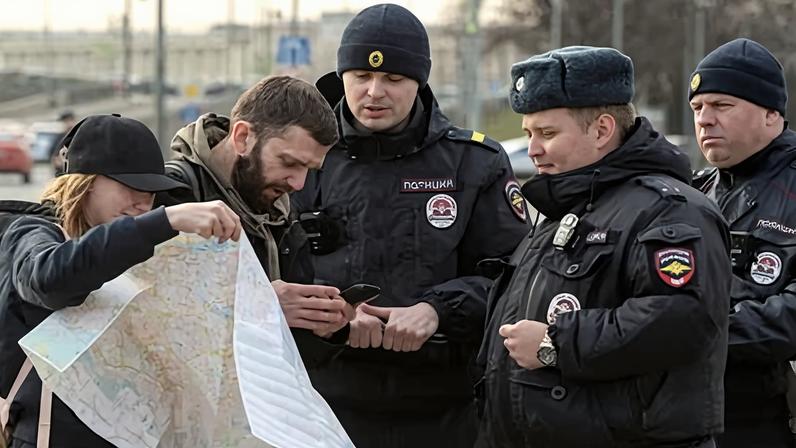 Police speak with a man and a woman carrying a paper map, symbolising the loss of access to phone navigation, during a protest in St Petersburg against internet restrictions.