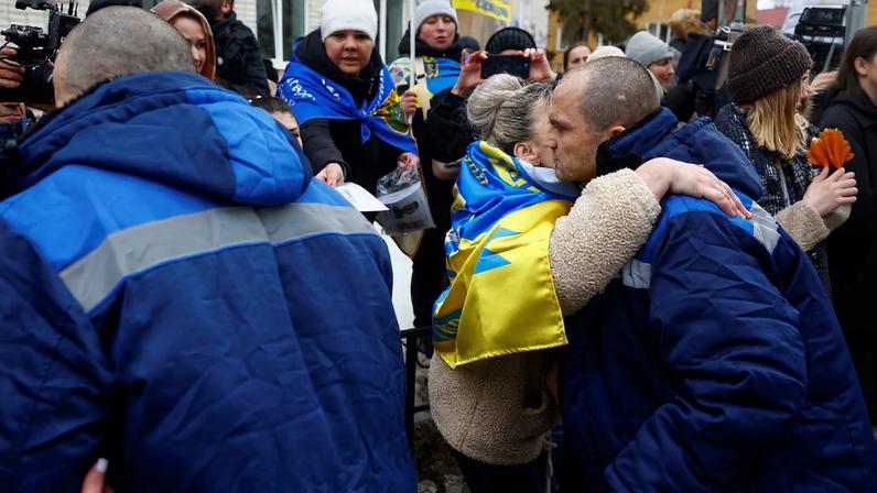 A woman embraces a freed Ukrainian prisoner of war (POW) while he leaves an ambulance van after a swap, amid Russia's attack on Ukraine, in an undisclosed location in Ukraine