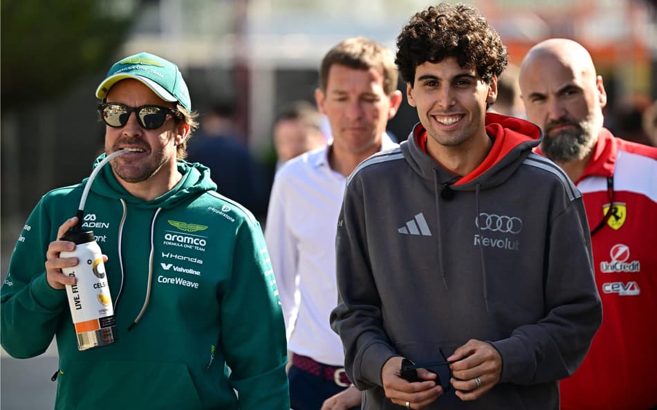 O espanhol da Aston Martin Fernando Alonso e o brasileiro da Audi Gabriel Bortoleto caminham pelo paddock no primeiro dia do segundo teste de pré-temporada da Fórmula 1 no Circuito Internacional do Bahrein, em Sakhir, em 18 de fevereiro de 2026 (Foto: Giuseppe cacace/afp)