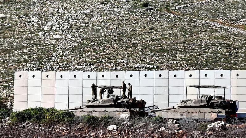 Israeli soldiers work on their tank on the Israeli side of the Israel-Lebanon border