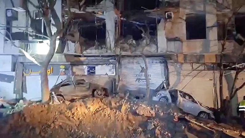 Un edificio y varios coches destrozados tras un ataque israelí en Teherán, esta noche.