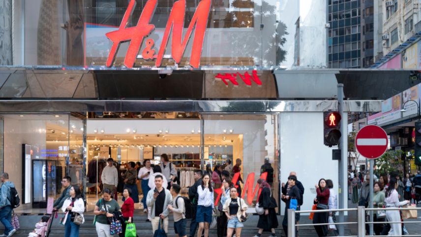 Pedestres e consumidores são vistos do lado de fora da rua, em frente à loja da multinacional sueca de design e varejo de roupas Hennes & Mauritz (H&M), em Hong Kong.