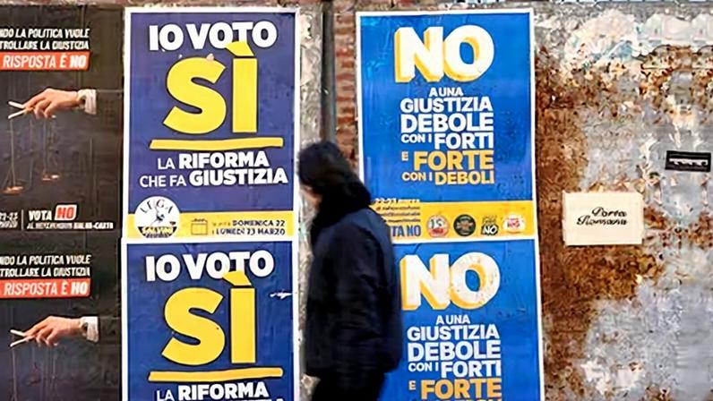 Un ciudadano pasa por una calle de Milán ante carteles electorales para el referéndum que se celebra el 22 y 23 de marzo.