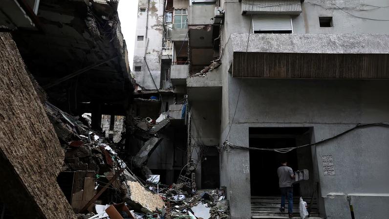 A man carries a ladder next to a damaged building in the aftermath of an Israeli strike in central Beirut, targeting what Israel said is a Hezbollah-affiliated bank, following an escalation between Hezbollah and Israel amid the U.S.-Israeli conflict with Iran, in Beirut, Lebanon, March 15, 2026.