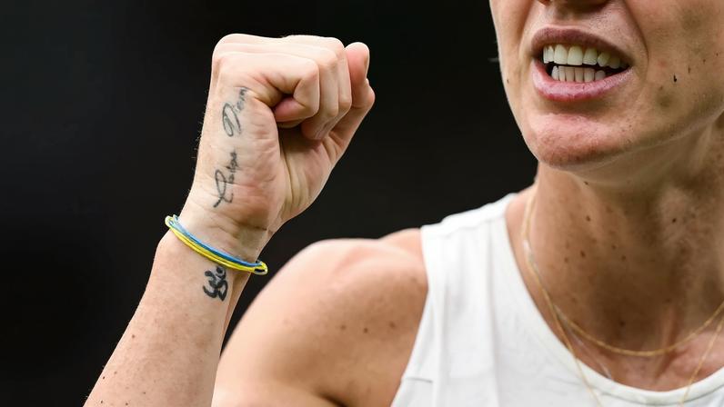 A tattoo reading "Carpe Diem" and a bracelet with the colors of the Ukrainian flag are pictured on the hand of Ukraine's Elina Svitolina.