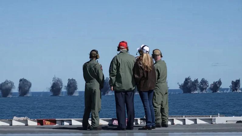 President Donald Trump and First Lady Melania Trump observe naval flight demonstrations on the deck of the USS George H.W. Bush aircraft carrier on October 5, 2025 off the eastern coast of the United States.