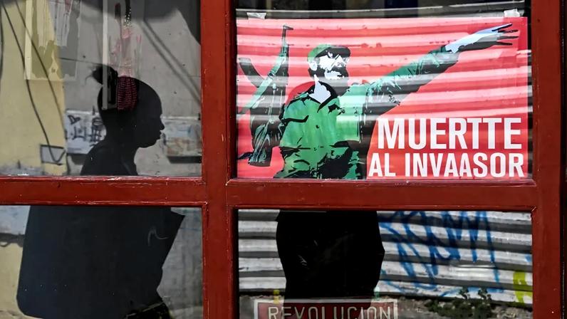 A woman walks past a poster of late Cuban leader Fidel Castro reading "Death to the invader" in Havana on March 13.