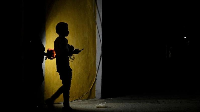 A woman holds a flashlight while walking on a street during a blackout in Havana on March 16.