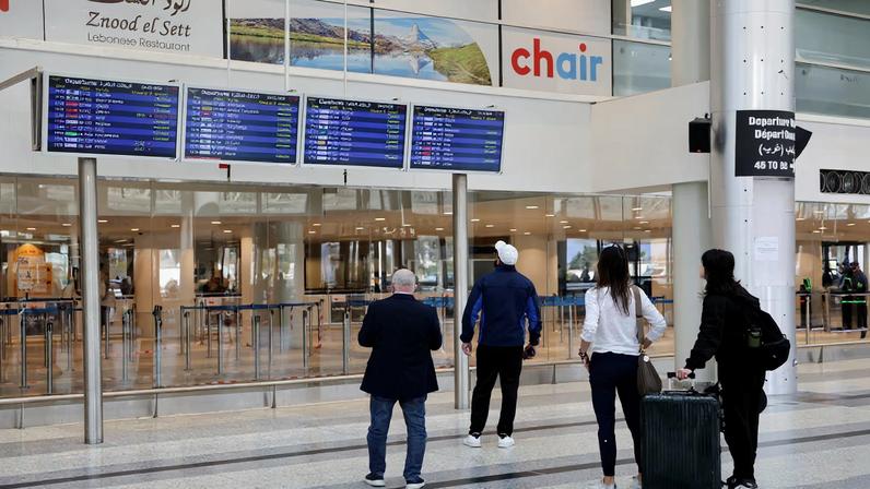 Passengers look at flight information boards at Beirut–Rafic Hariri International Airport, following an escalation between Hezbollah and Israel, amid the U.S.-Israel conflict with Iran