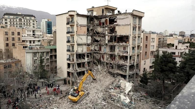 An excavator clears rubble from destroyed residential buildings in Tehran.