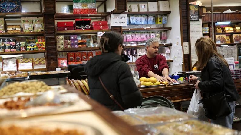 A pre-Iranian Revolution "Lion and Sun" flag is displayed as customers shop at Tavazo, a Persian patisserie in Finchley, London