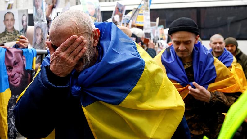 Freed Ukrainian prisoners of war (POWs) react while they leave a bus after a swap, amid Russia's attack on Ukraine, in an undisclosed location in Ukraine