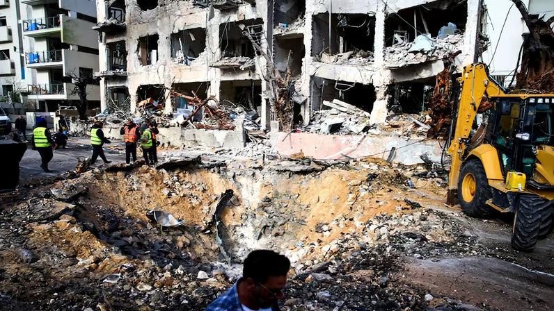 Trabajadores de emergencias y militares inspeccionan el lugar del impacto tras un ataque iraní en Tel Aviv este domingo.