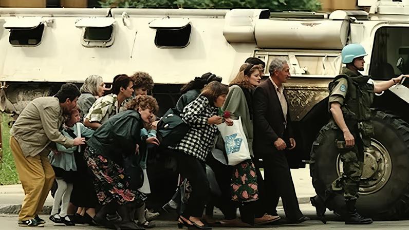 Ciudadanos de Sarajevo, Bosnia, se protegen de disparos de francotiradores tras un carro de combate de la ONU en 1995.