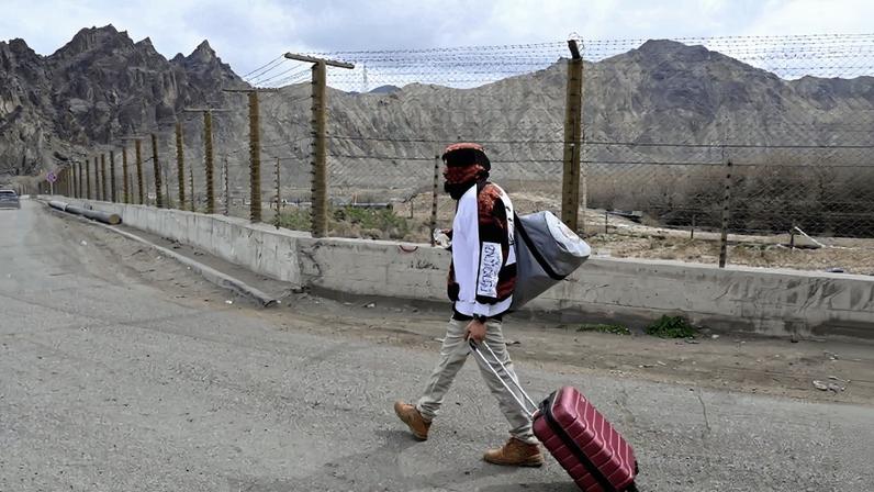 An Iranian refugee walks with his belongings after crossing the border from Iran to Armenia in the southern Armenian town of Meghri.