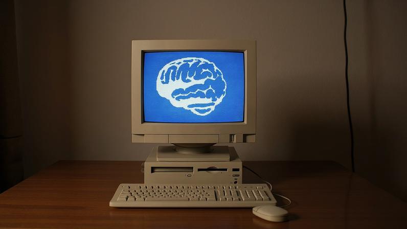 A vintage computer on a background of 1s and 0s with a brain on the screen representing AI