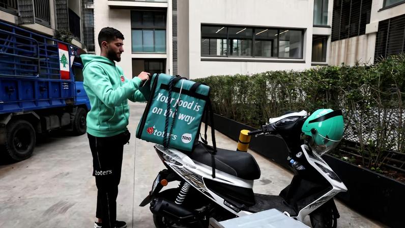 Hamza Hareb, who works as a delivery driver for the Toters delivery app opens his courier's backpack to drop a delivery in Beirut