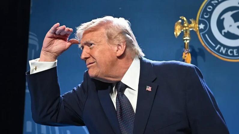 Trump is shown from the side as he peers ahead, with his hand shielding the top of his head.
