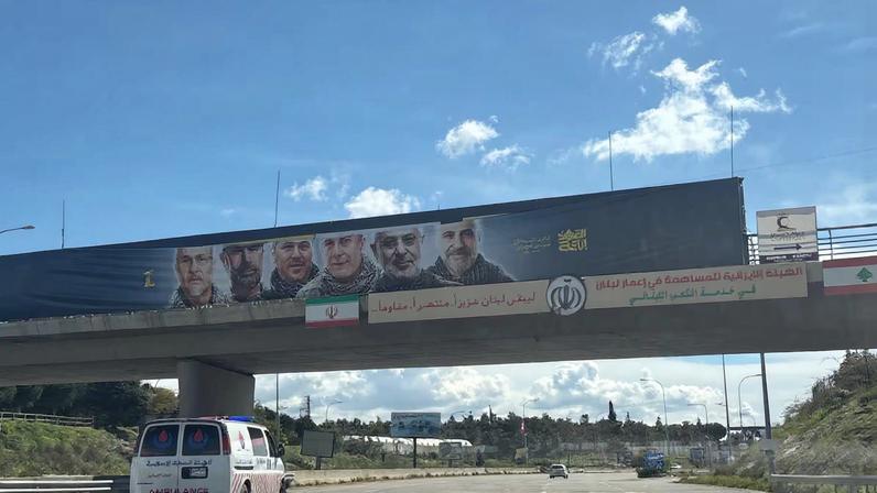 Una ambulancia circula hacia el sur de Líbano bajo un puente con la bandera iraní, este miércoles.