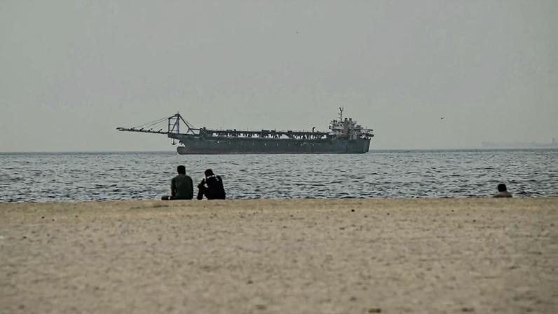 People watch a vessel in the Persian Gulf from a beach in the United Arab Emirates on March 2.