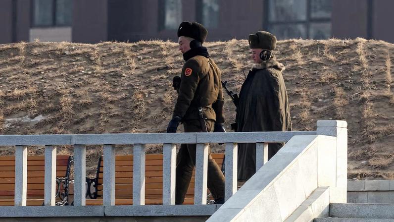 North Korean servicemen walk at a newly constructed embankment in Hadan district of Sinuiju, seen from Dandong
