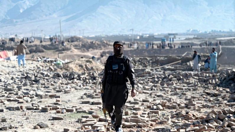 A Taliban security officer walks past rubble at the site of a Pakistani airstrike on the outskirts of Kabul on March 13.