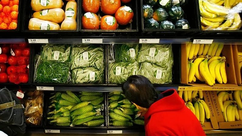 Getty Images Consumidor em frente à gôndola de frutas e vegetais em supermercado