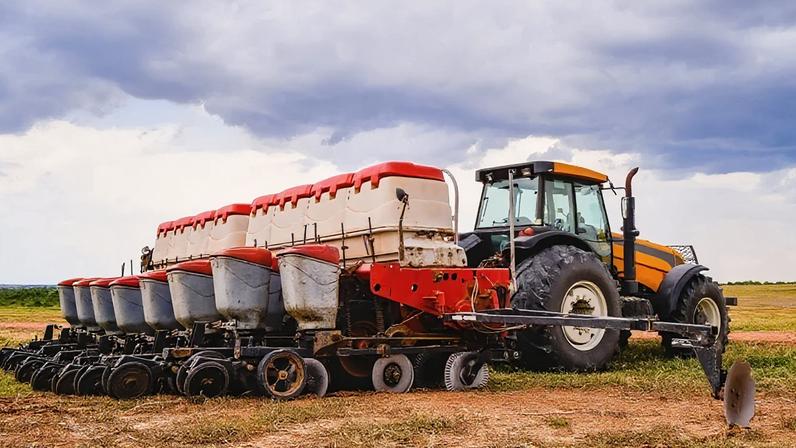 Trator com implemento de plantadeira agrícola no campo