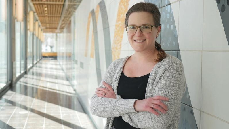 Alison Ringel poses in a hallway with glass walls on one side